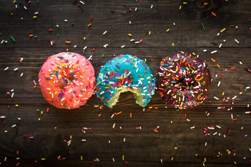 Süßer Geschmack: Drei Donuts mit bunter Glasur und Zuckerstreuseln 