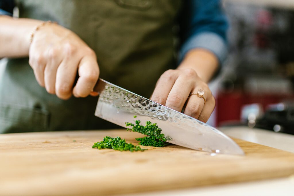 Schnittlauch wird mit Kochmesser (Wiegemesser) geschnitten.